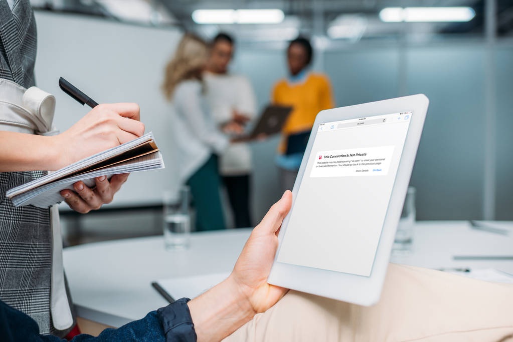 Geschäftsmann hält Tablet mit Browser-App auf dem Bildschirm im modernen Büro, während Kollege Notizen macht - Foto, Bild