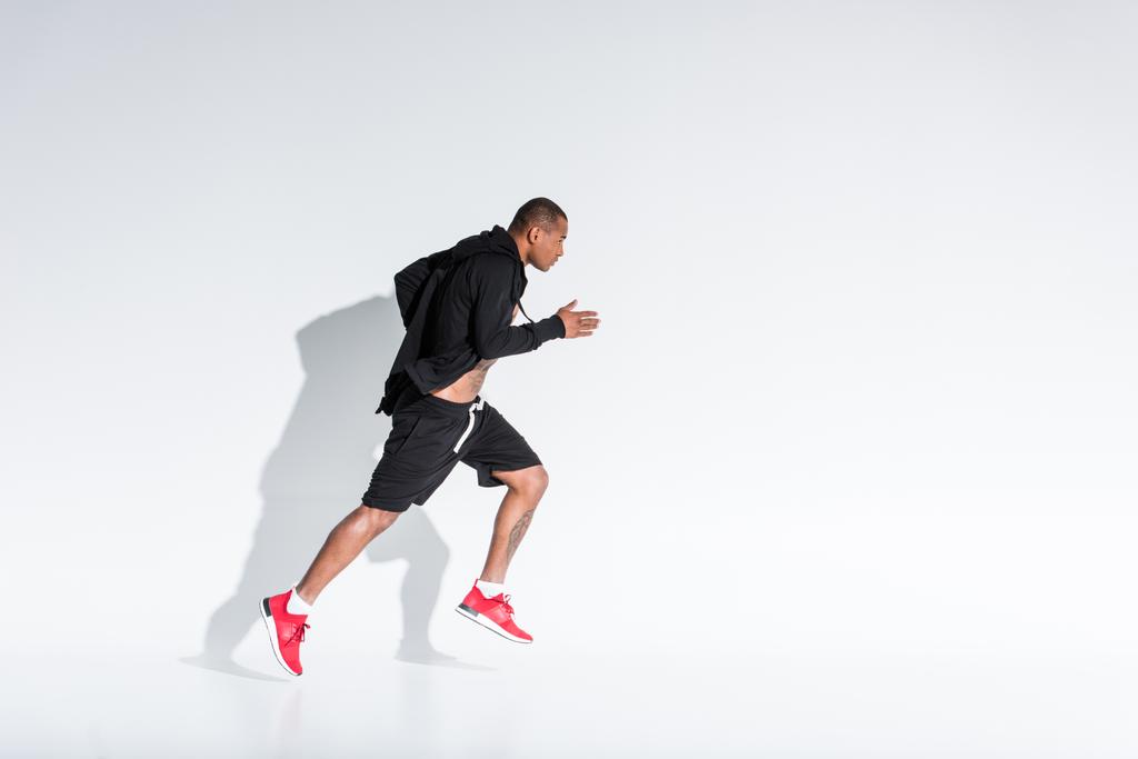 vista lateral do jovem esportista afro-americano em sportswear correndo em cinza
 - Foto, Imagem