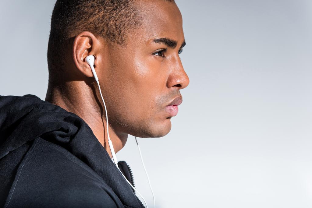 retrato de perfil del joven afroamericano escuchando música en auriculares y mirando hacia otro lado aislado en gris
 - Foto, Imagen