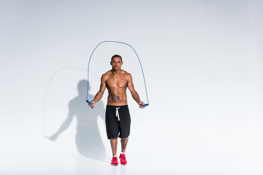 shirtless αφροαμερικάνος αθλητής άσκηση με σχοινάκι σε γκρι - Φωτογραφία, εικόνα