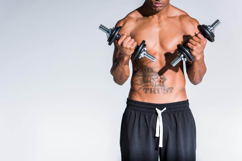 περικοπεί shot από shirtless αφροαμερικάνος αθλητής άσκηση με βάρη που απομονώνονται σε γκρι - Φωτογραφία, εικόνα