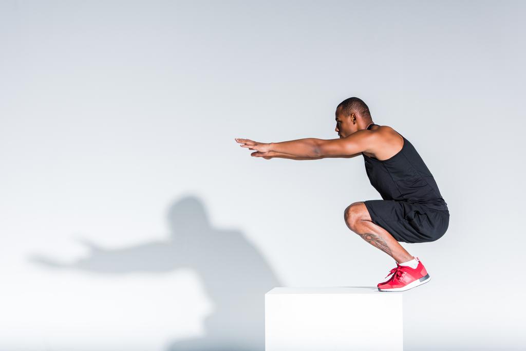 вид збоку молодого афроамериканського спортсмена, готового стрибати на сірий
 - Фото, зображення