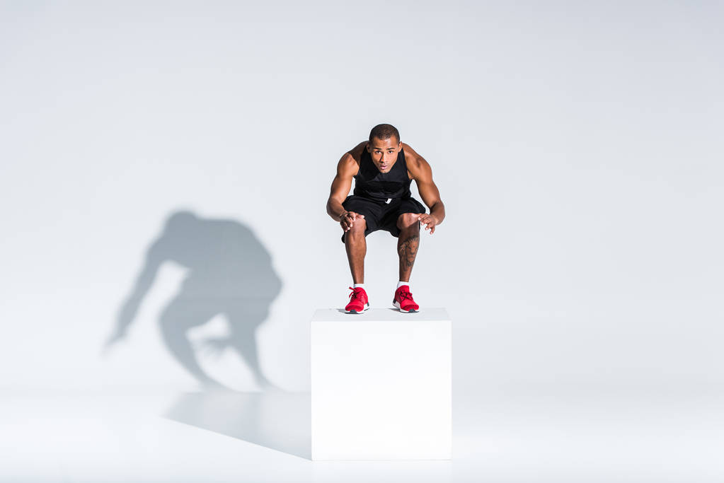 atlama ve kameraya gri görünümlü genç Afro-Amerikan sporcu görünümünü tam uzunlukta  - Fotoğraf, Görsel