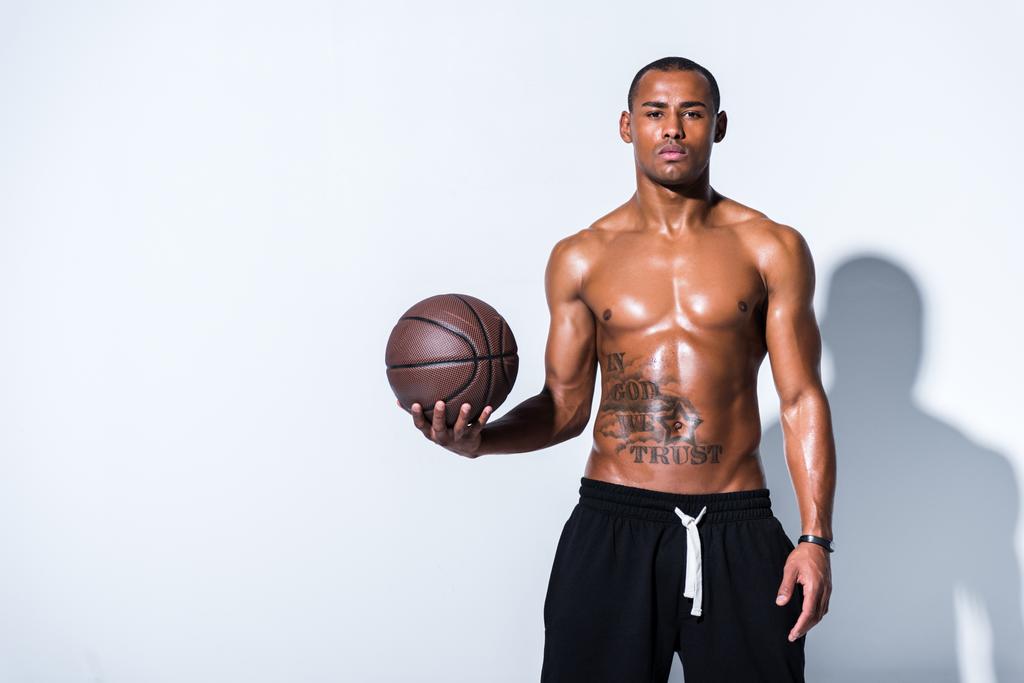 athlétique torse nu homme afro-américain avec ballon de basket regardant caméra sur gris
  - Photo, image
