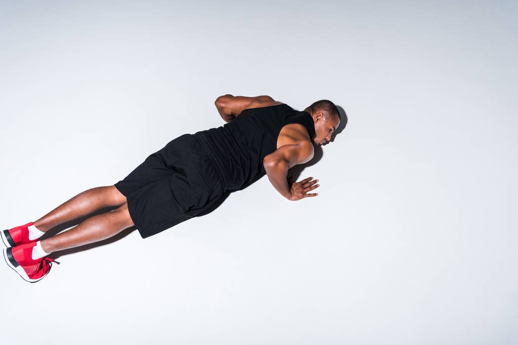 high angle view of young african american sportsman doing push ups isolated on grey  - Photo, Image