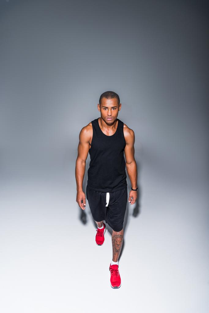 vue grand angle du jeune sportif afro-américain marchant sur le gris
 - Photo, image