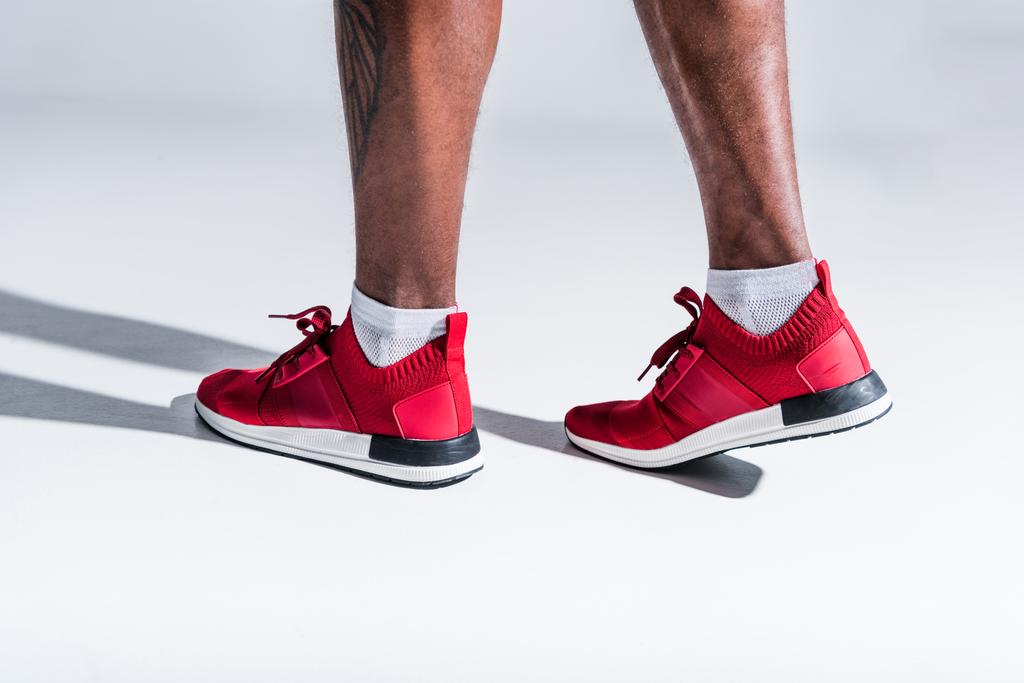 plan recadré de l'homme afro-américain en chaussures de sport sur gris
  - Photo, image
