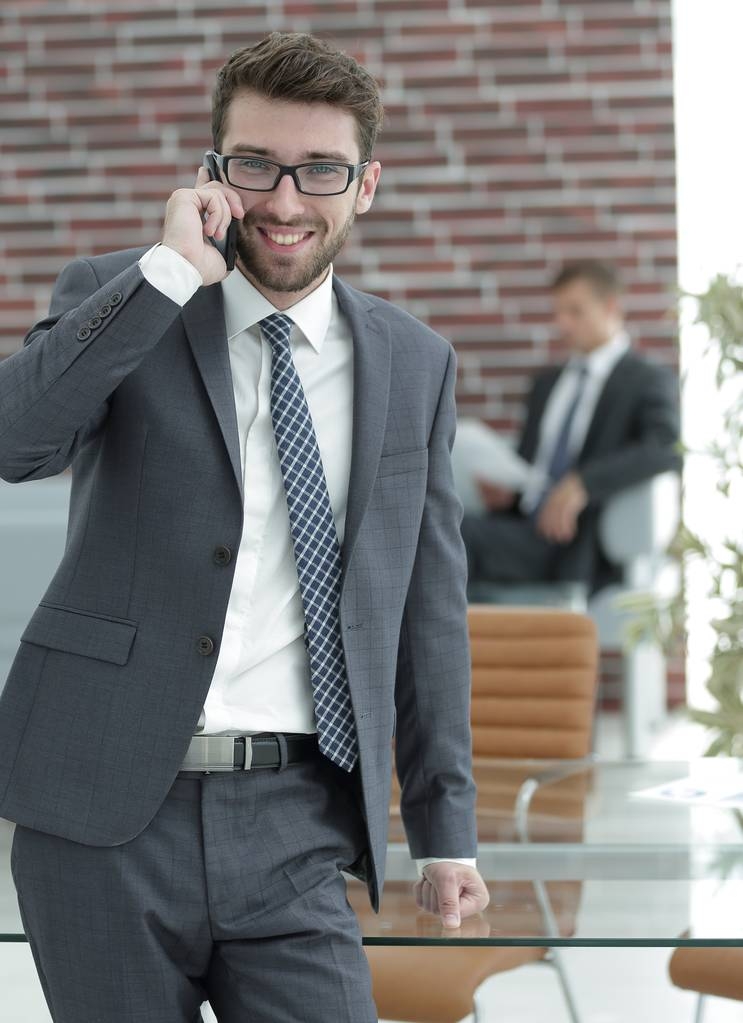 бизнесмен разговаривает на смартфоне в своем офисе
 - Фото, изображение