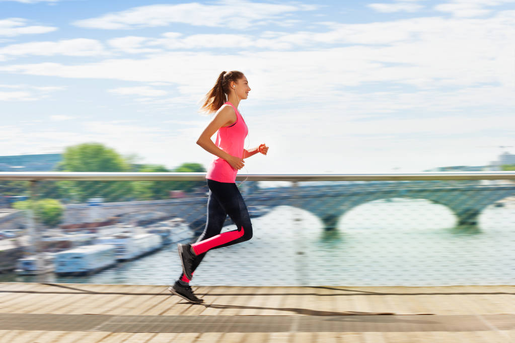 Μερική άποψη του ενεργού νεαρή γυναίκα σε αθλητικά ενδύματα που τρέχει πέρα από μια γέφυρα - Φωτογραφία, εικόνα