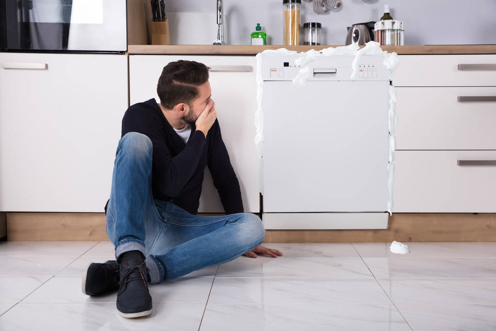 Человек, сидящий рядом с посудомоечной машиной
 - Фото, изображение