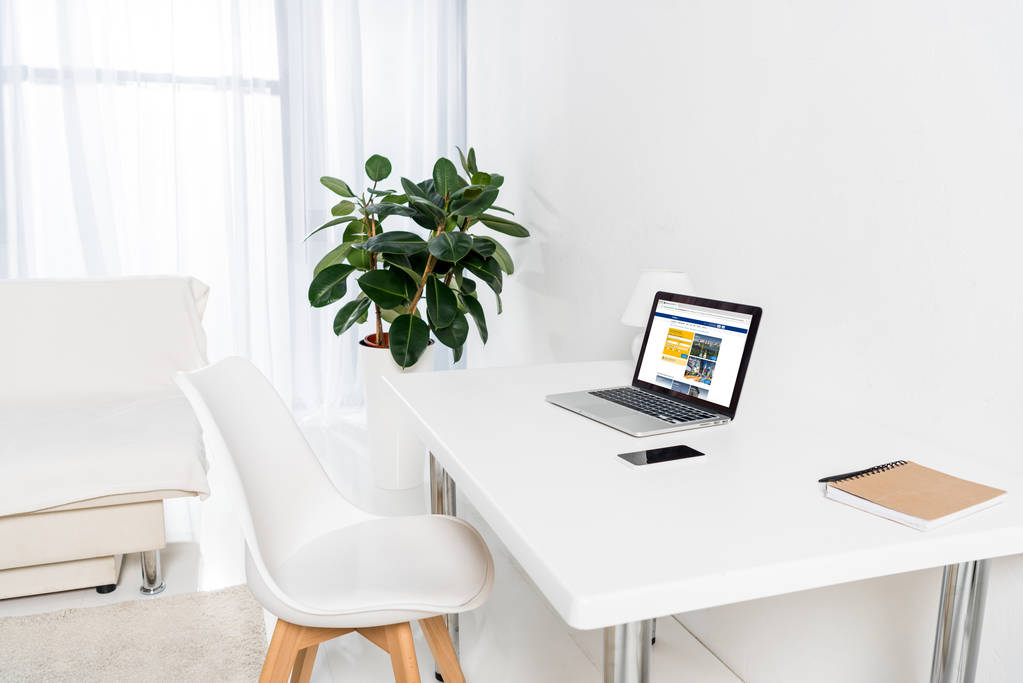escritório em casa com laptop com logotipo bookingcom, smartphone e notebook na mesa
 - Foto, Imagem