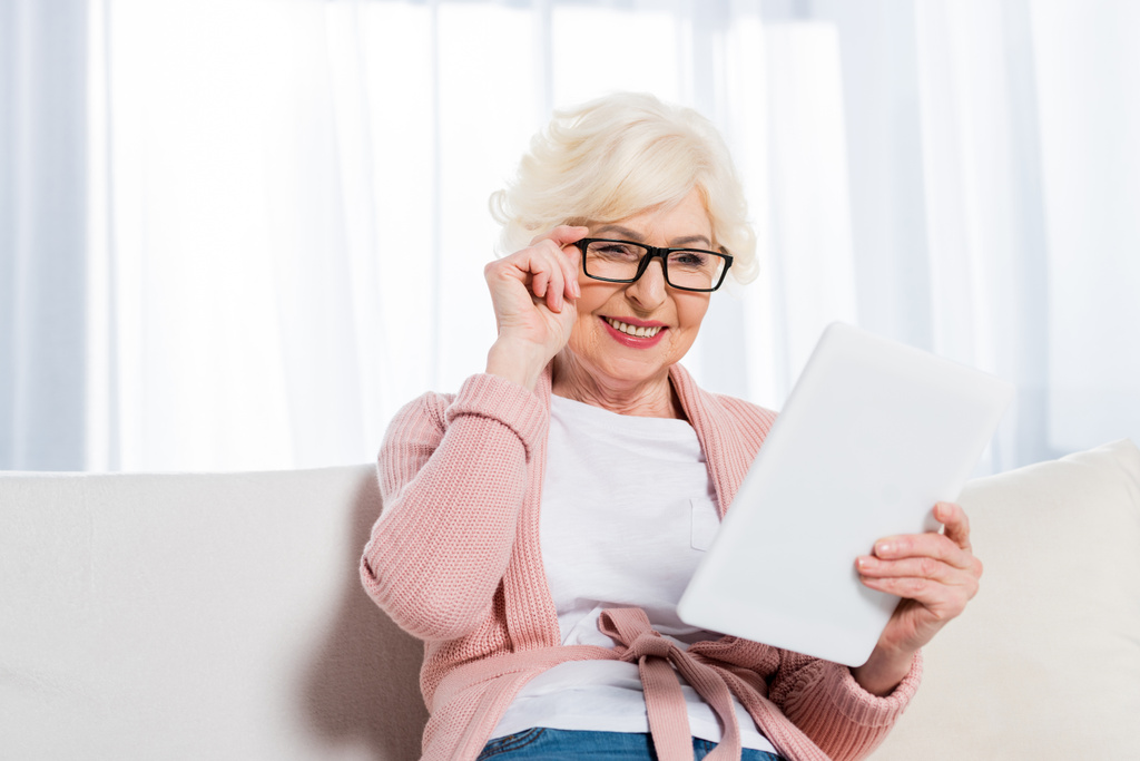 portrét usmívající starší žena v brýlích pomocí tabletu doma - Fotografie, Obrázek