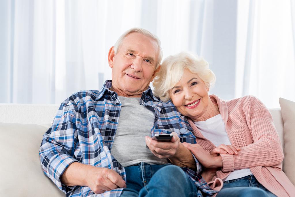 senior couple with remote control watching tv on couch - Photo, Image