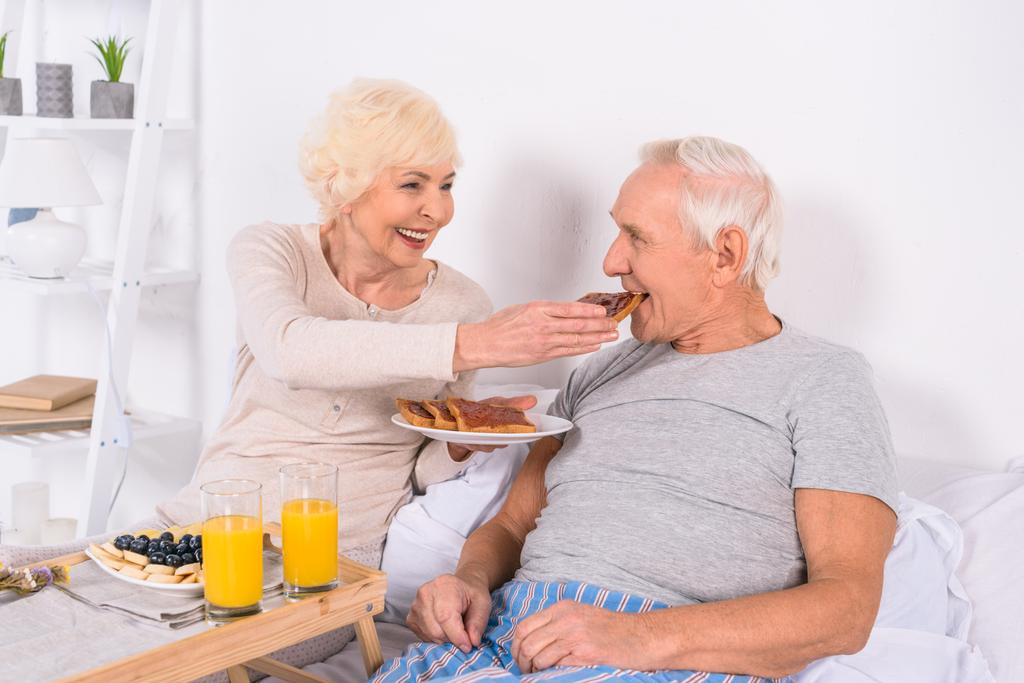 feliz pareja de ancianos desayunando en la cama juntos en casa
 - Foto, Imagen