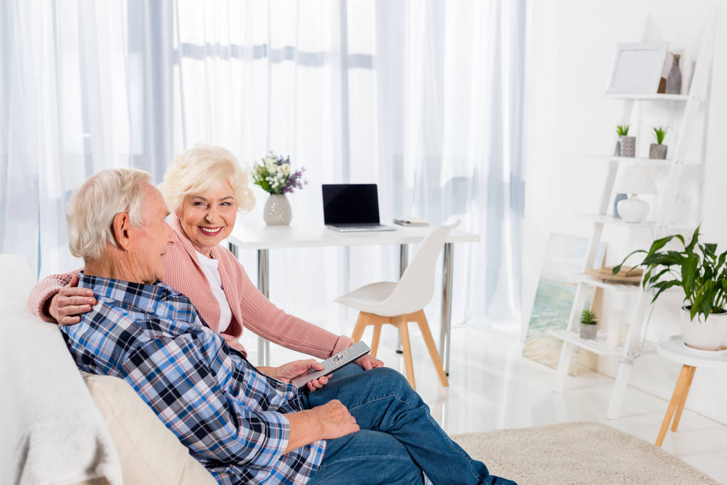 szczęśliwa para starszy siedzi na kanapie w domu i mówić - Zdjęcie, obraz