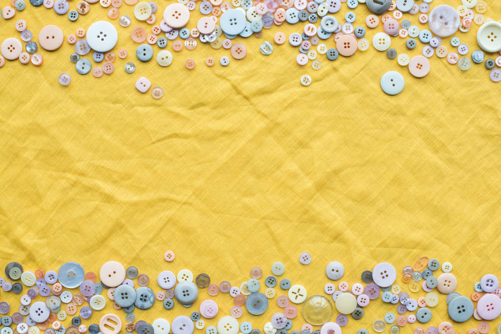 vue de dessus du cadre de boutons colorés sur fond de tissu jaune avec espace de copie
 - Photo, image