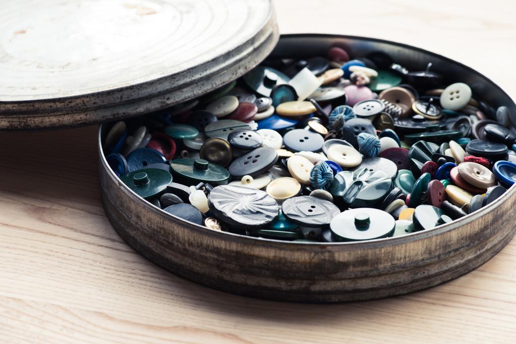 muchos botones en caja circular sobre fondo de madera
 - Foto, imagen