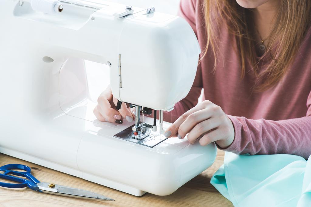 cropped image of young seamstress using sewing machine at workplace - Photo, Image