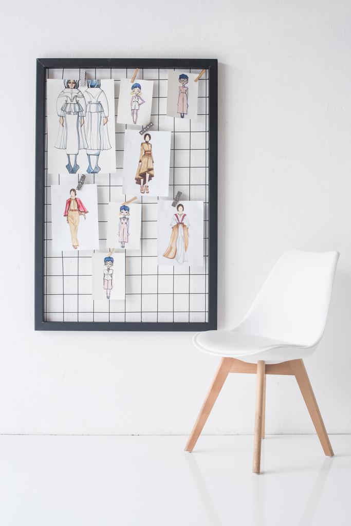 black frame with sketches on wall and chair in white room - Photo, Image