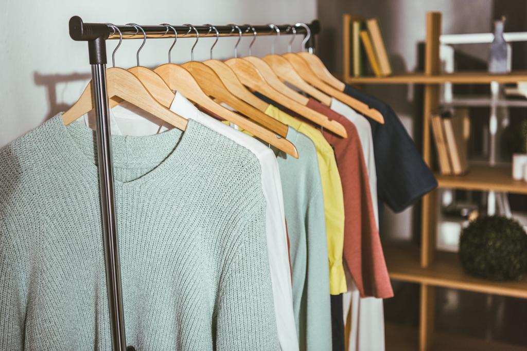 suéteres y camisas de diferentes colores en perchas
  - Foto, imagen
