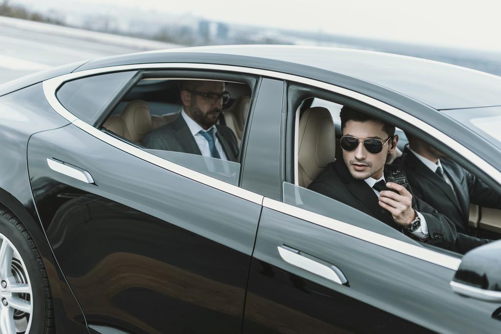 lijfwachten en zakenman zitten in een zwarte auto  - Foto, afbeelding
