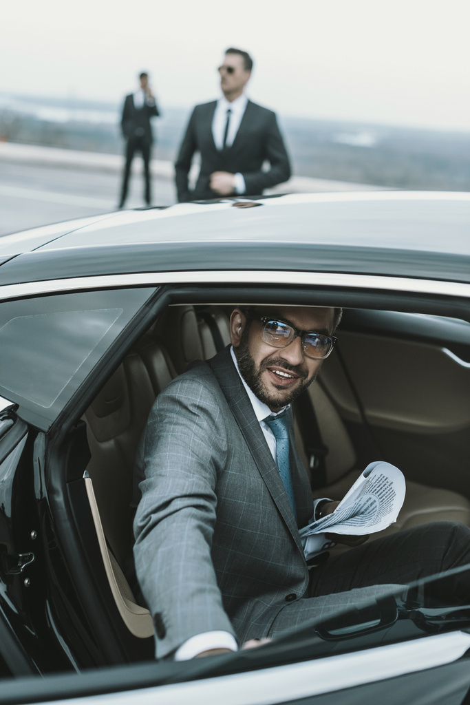 lachende zakenman in glazen uitgaan uit auto - Foto, afbeelding