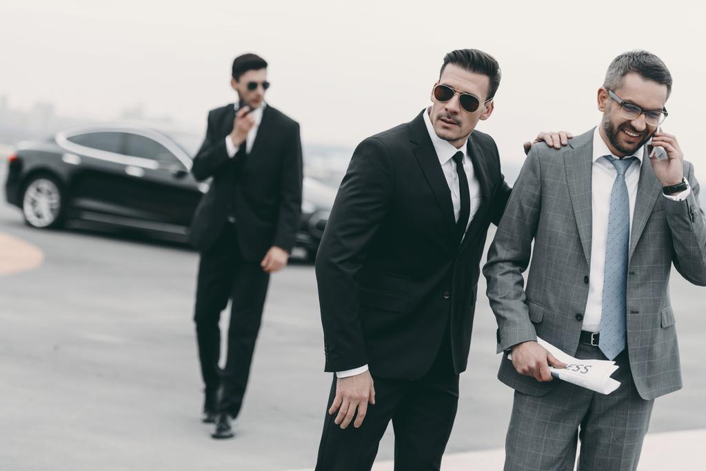 šťastný podnikatel chodí s bodyguardy a mluví o smartphone - Fotografie, Obrázek