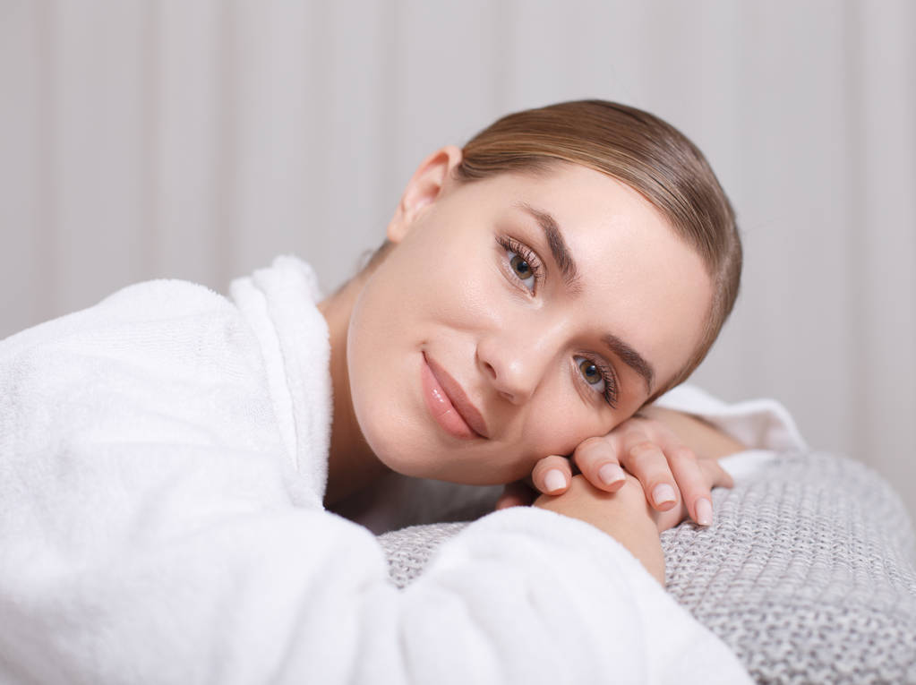 Entspannte junge Frau liegt im Schönheitssalon im Bett - Foto, Bild