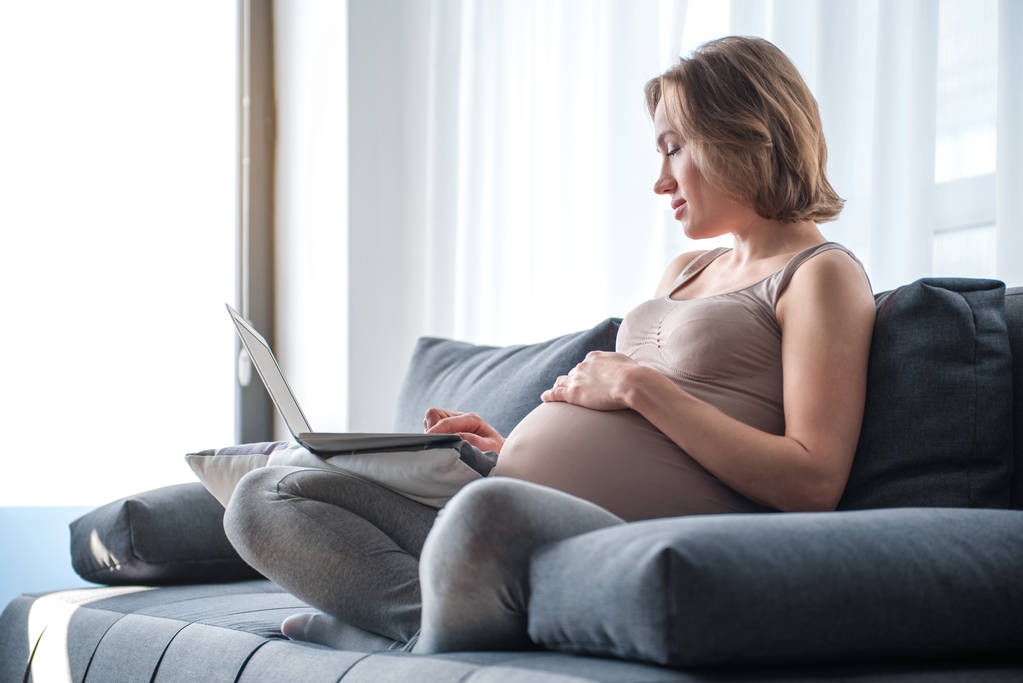 Ruhige werdende Mutter schaut sich Video auf tragbarem Computer an - Foto, Bild