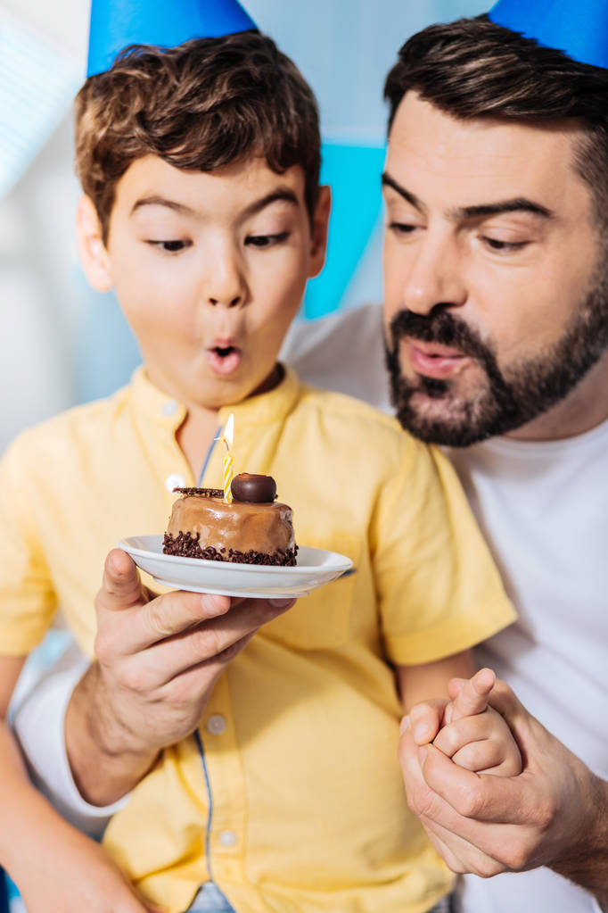 père aider son fils souffler bougie sur gâteau
 - Photo, image