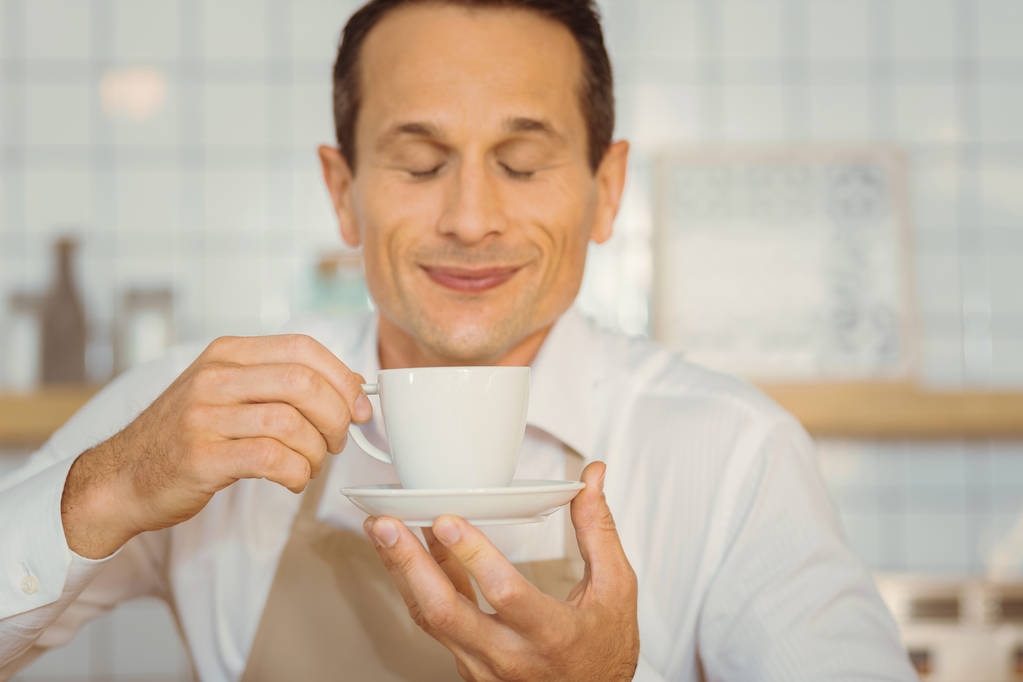 Восхитительный позитивный человек пробует кофе
 - Фото, изображение