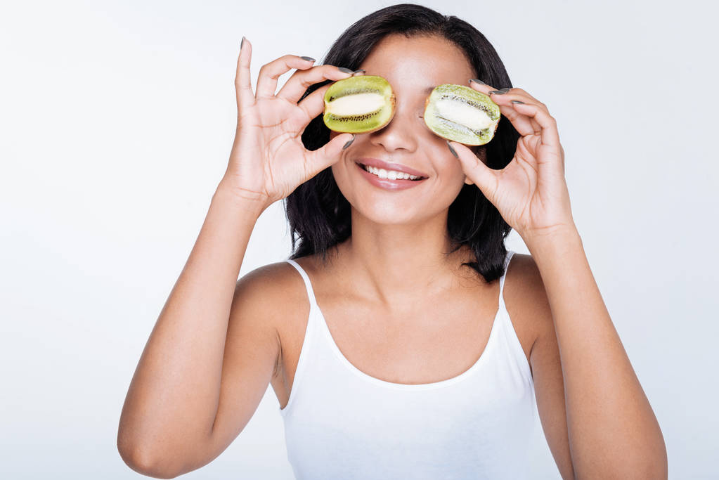 woman posing with kiwifruits near her eyes - Photo, Image