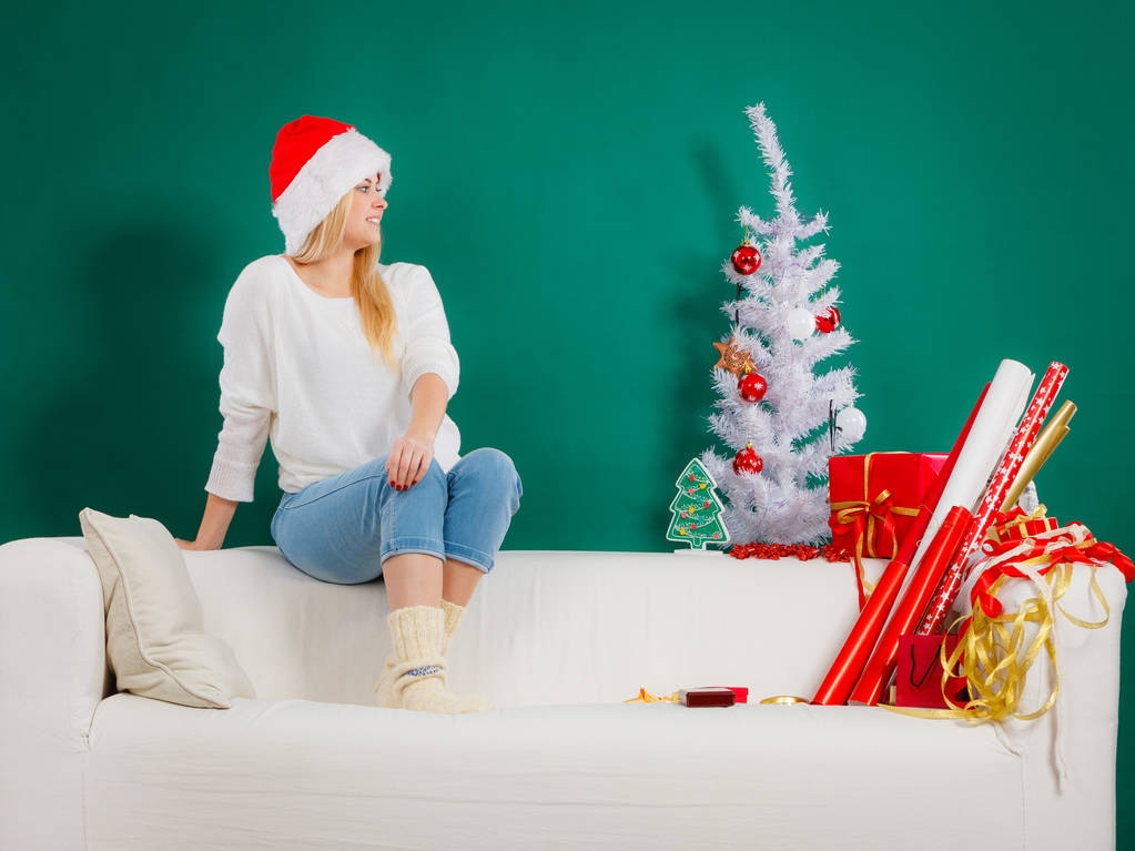 Mujer en Santa sombrero sentado en el sofá relajante
 - Foto, imagen