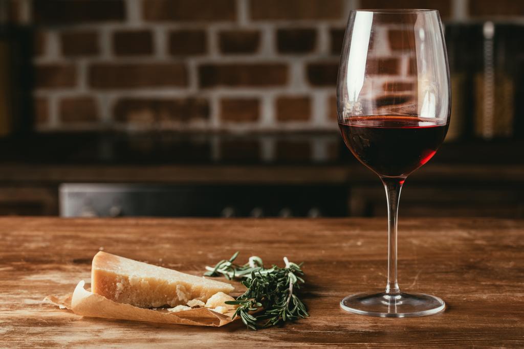 pohár vörös bor, parmezán sajt, friss rozmaring, a fából készült asztallap - Fotó, kép