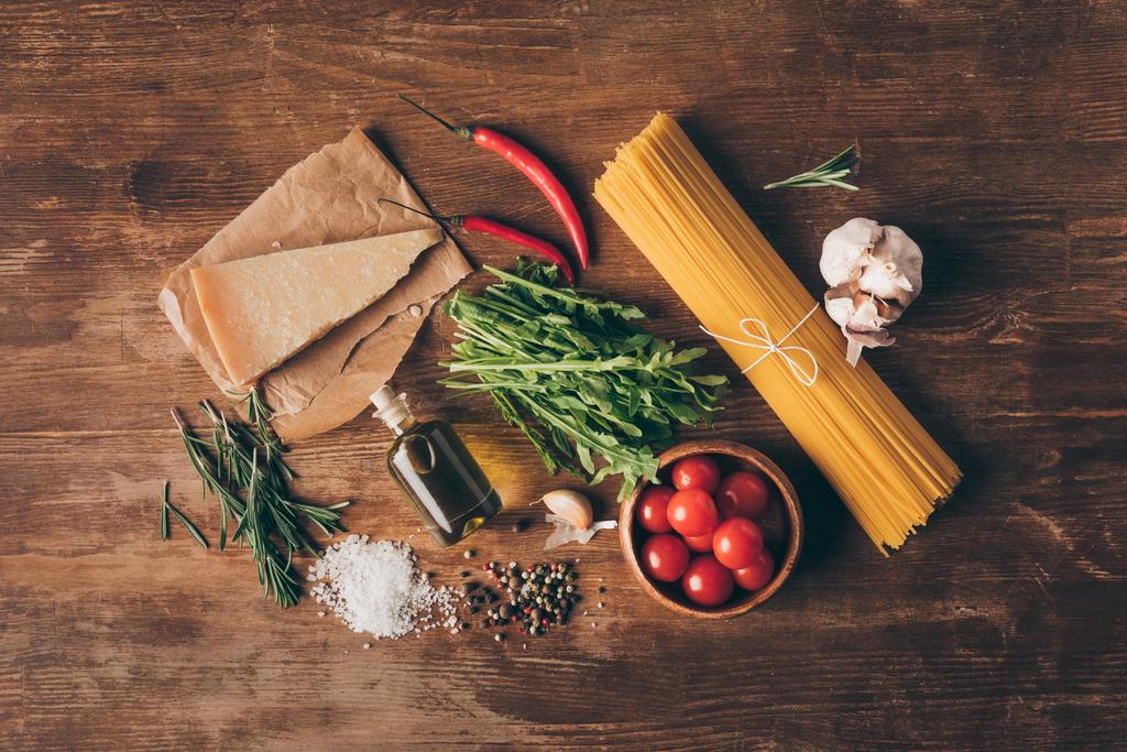 bovenaanzicht van traditionele rij pasta en verse ingrediënten op houten tafelblad - Foto, afbeelding