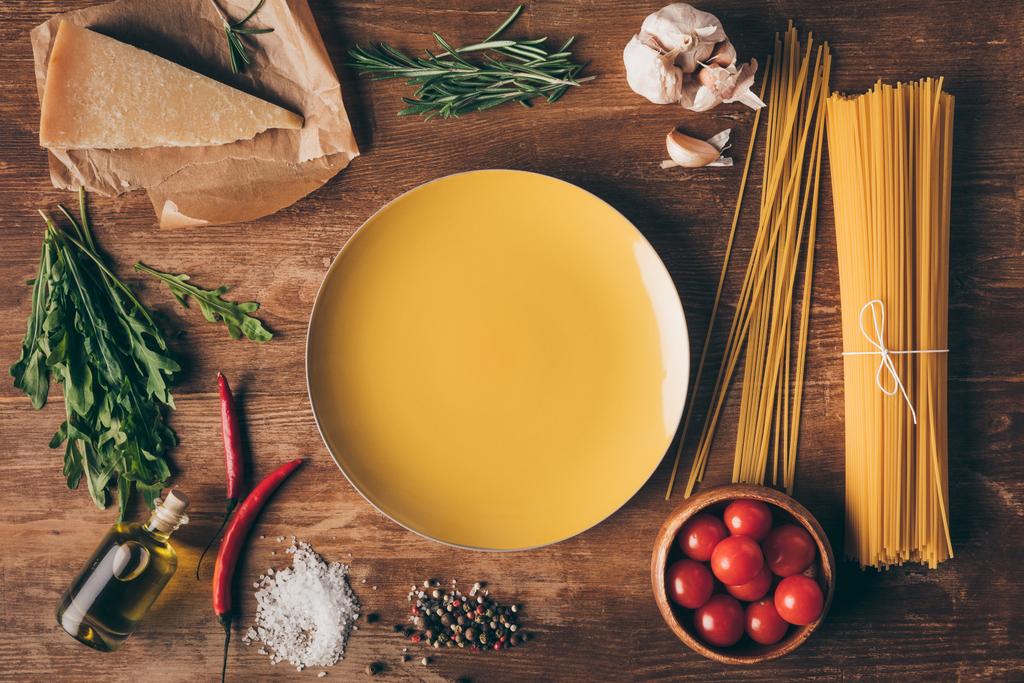 top view of row pasta, fresh ingredients and plate on wooden table - Photo, Image