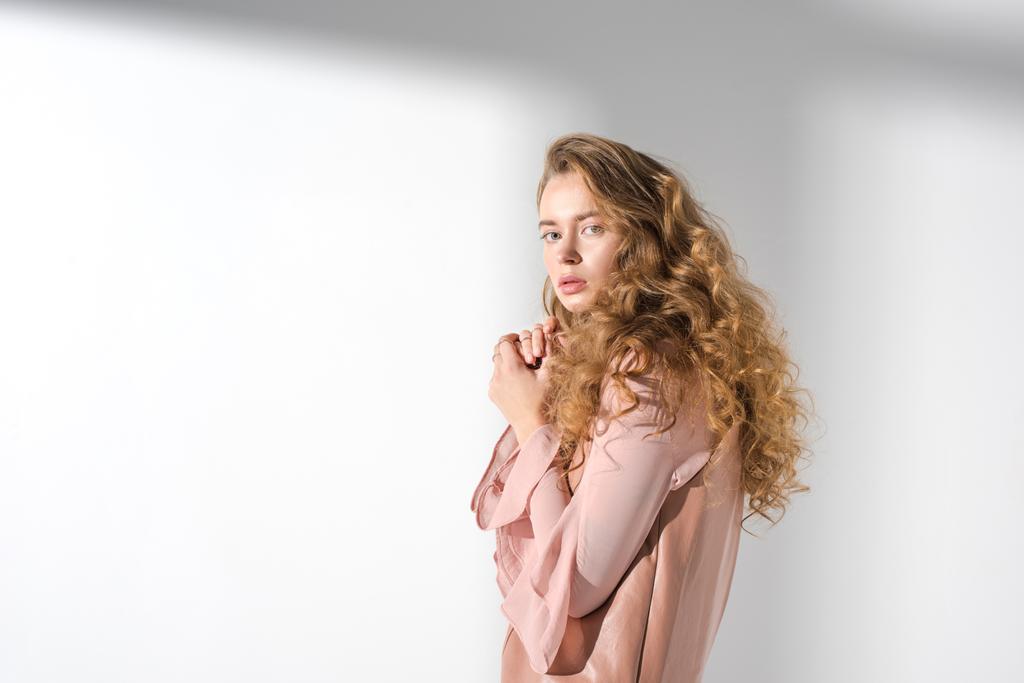 confused girl in beige dress with curly hair looking at camera - Photo, Image