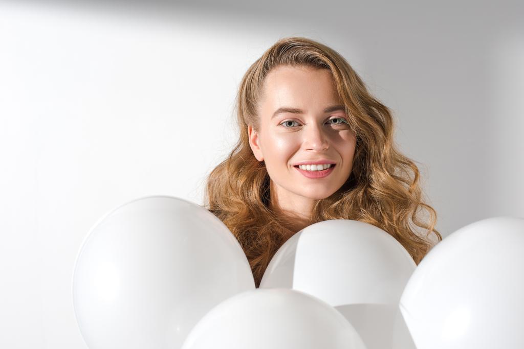 χαμογελώντας όμορφου κορίτσι στέκεται με λευκά μπαλόνια με ήλιο - Φωτογραφία, εικόνα