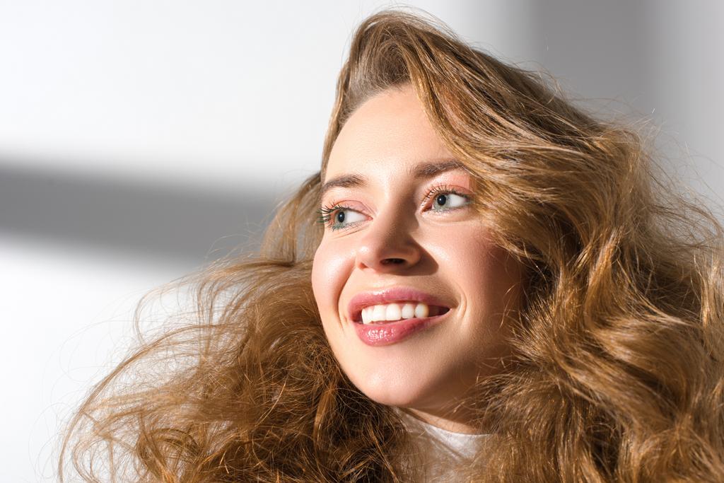 портрет улыбающейся девушки с кудрявыми волосами, смотрящей в сторону
 - Фото, изображение