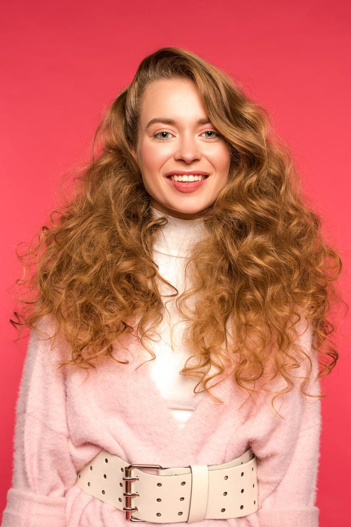 Stylový usmívající se žena s kudrnatými vlasy izolované na červené - Fotografie, Obrázek