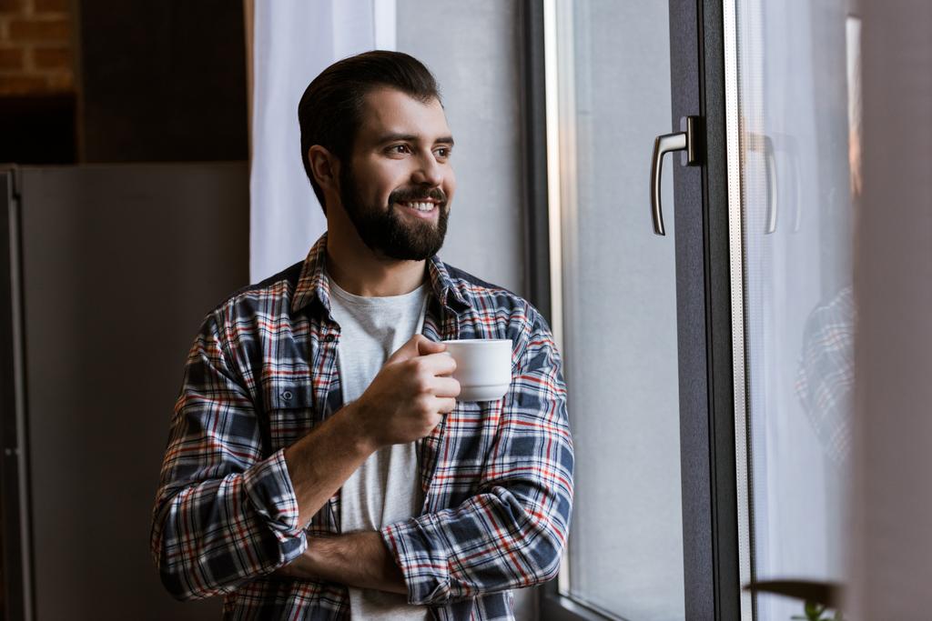 kahve fincanı penceresine bakarak mutlu yakışıklı adam - Fotoğraf, Görsel