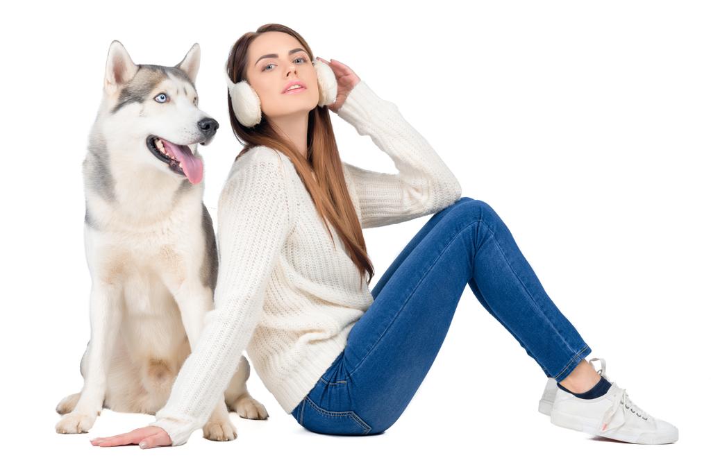 husky hond en charmante vrouw in winter oorkappen, geïsoleerd op wit - Foto, afbeelding
