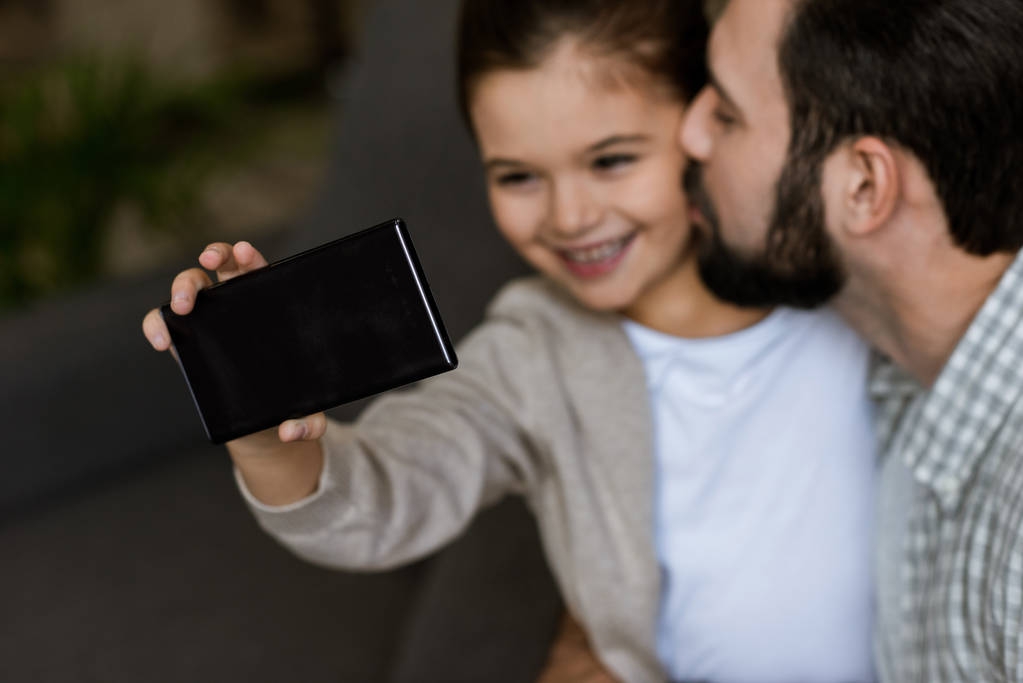 χαρούμενα πατέρα με κόρη λαμβάνοντας αυτοπορτρέτα στο smartphone στο σπίτι - Φωτογραφία, εικόνα