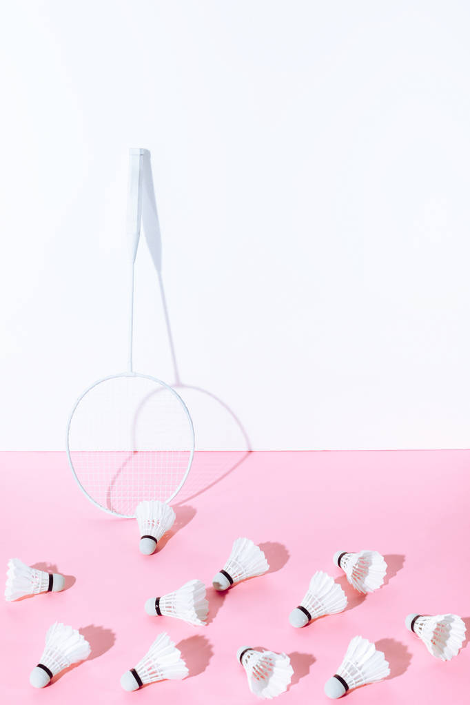 witte badminton racket en shuttles op roze papier op muur - Foto, afbeelding