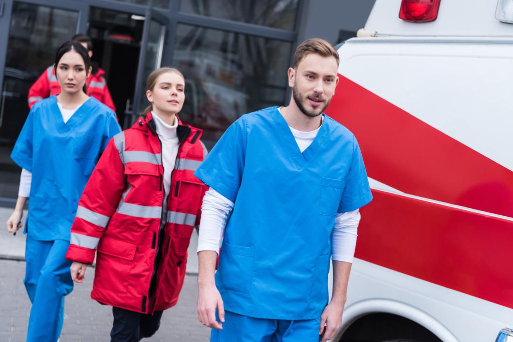 молода чоловіча і жіноча парамедики ходять біля швидкої допомоги
 - Фото, зображення