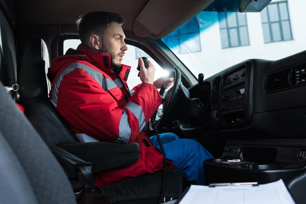 携帯ラジオで話している若いハンサムな男性救急救命士 - 写真・画像