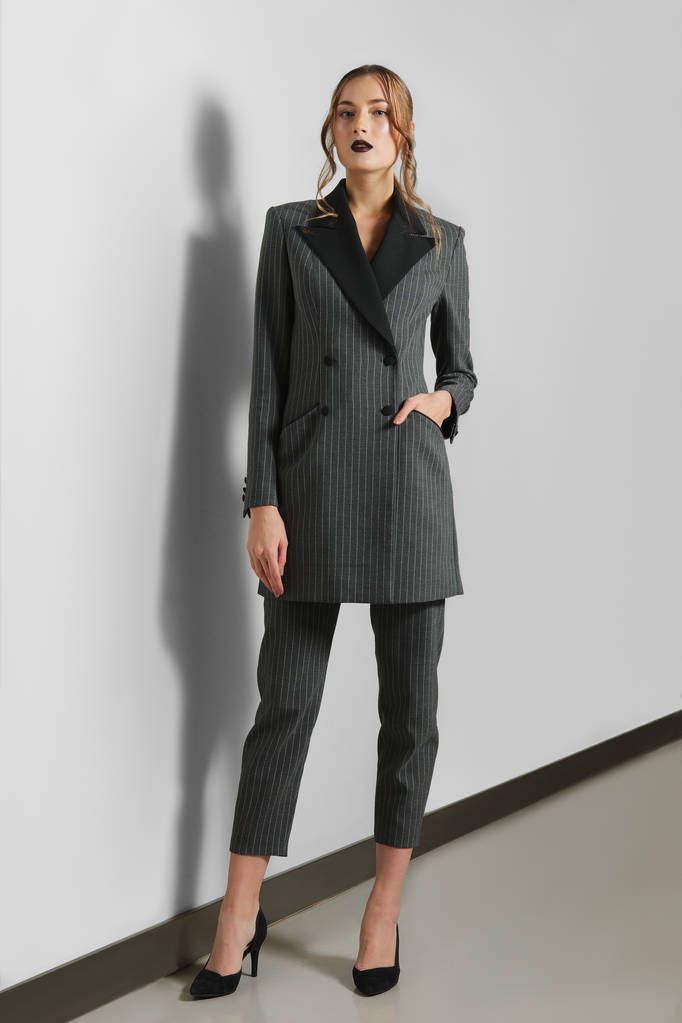 Приваблива модель в двобортній куртці і жорстких струнких брюках
 - Фото, зображення