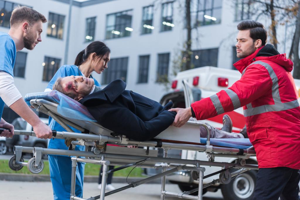 médicos moviendo hombre herido en camilla de ambulancia
 - Foto, imagen