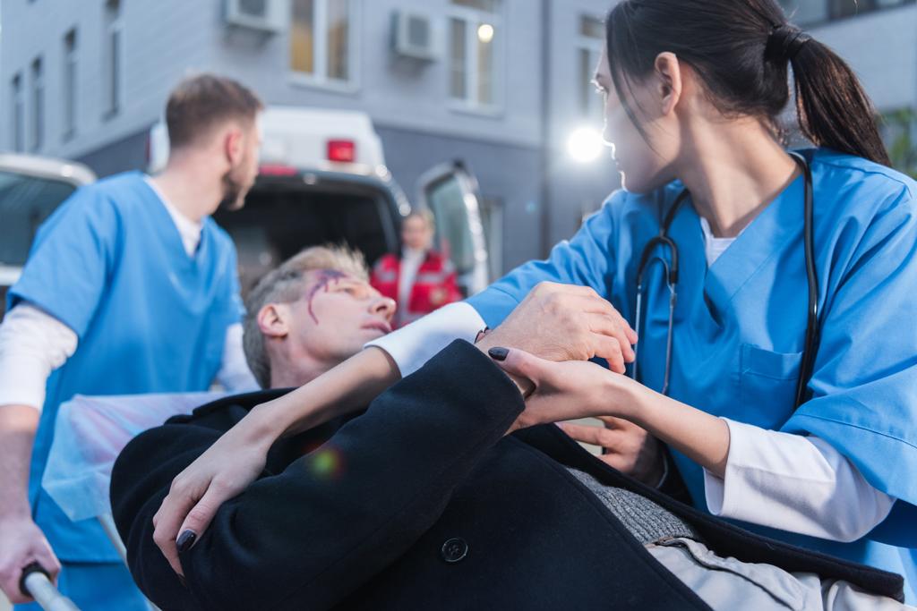 Sanitäter transportieren verletzten Mann auf Krankentransporttrage - Foto, Bild