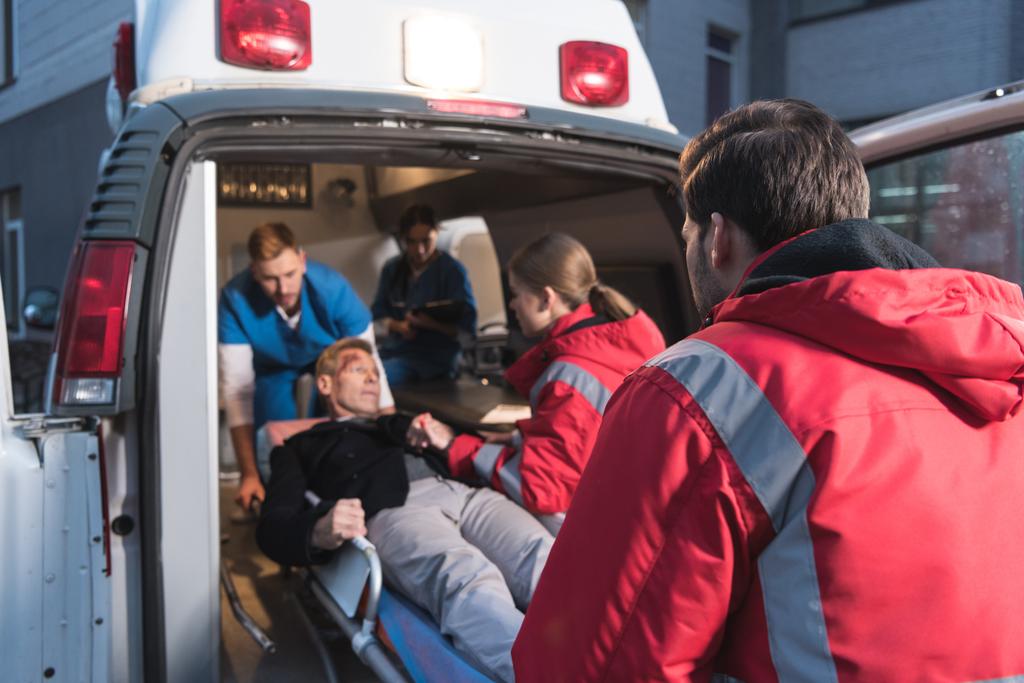 equipo de paramédicos moviendo hombre maduro herido en ambulancia
 - Foto, imagen
